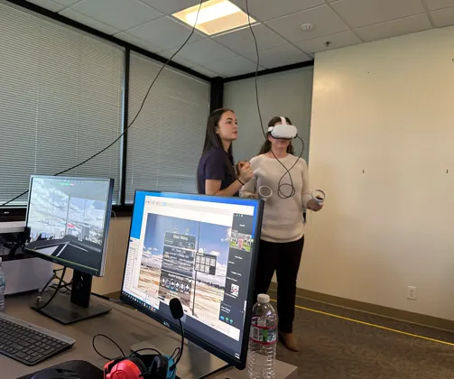 Woman instructing another woman about 3D VR headset