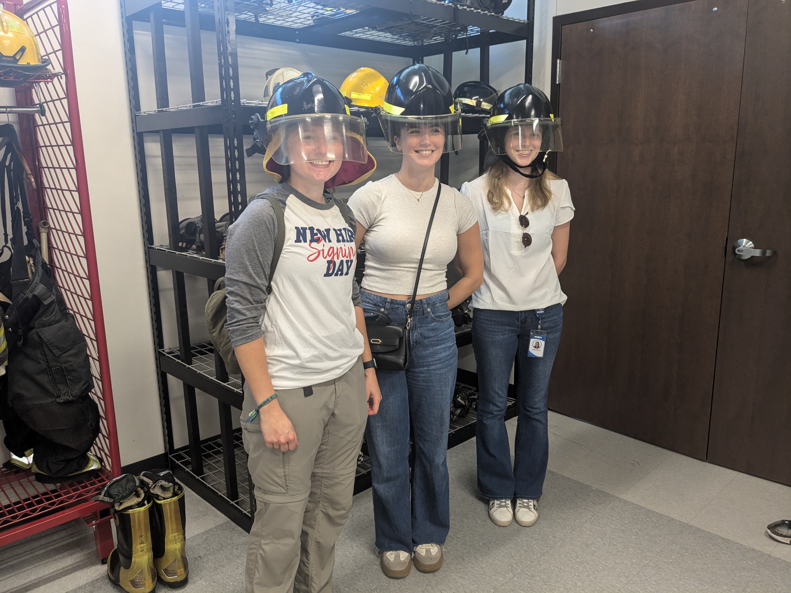 Three Pond interns trying on firefighter helmets.